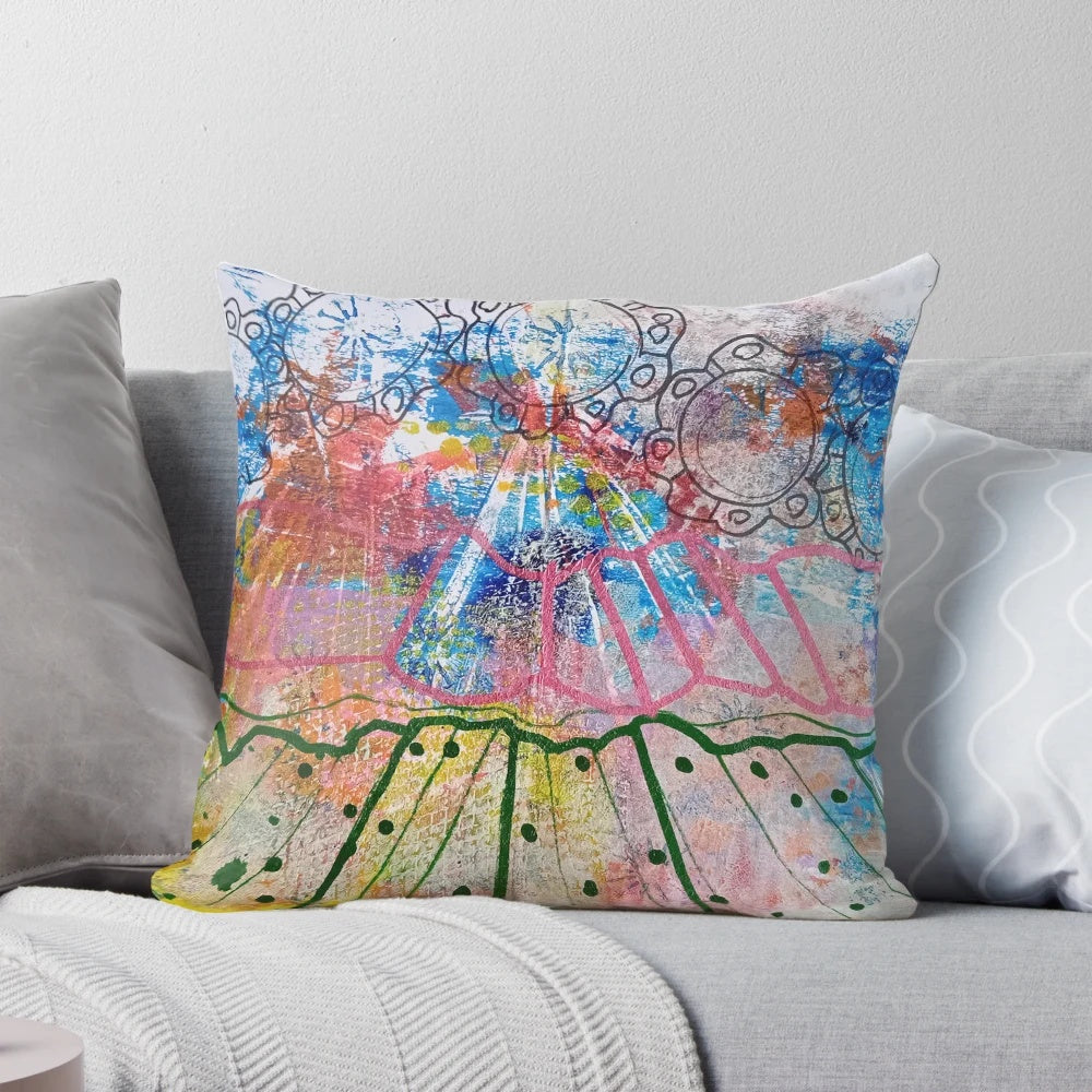 Vibrant abstract watercolor landscape design with radiating blue, green, and pink brush strokes and swirling yellow circles on a pillow.