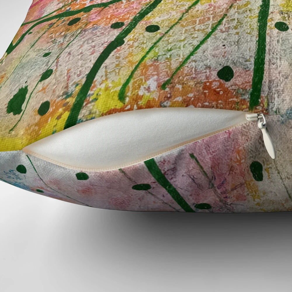 Vibrant abstract watercolor landscape design with radiating blue, green, and pink brush strokes and swirling yellow circles on a pillow.