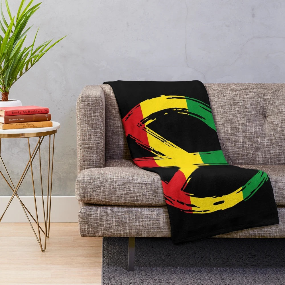 Plush black blanket with peace symbol in rastafarian colors