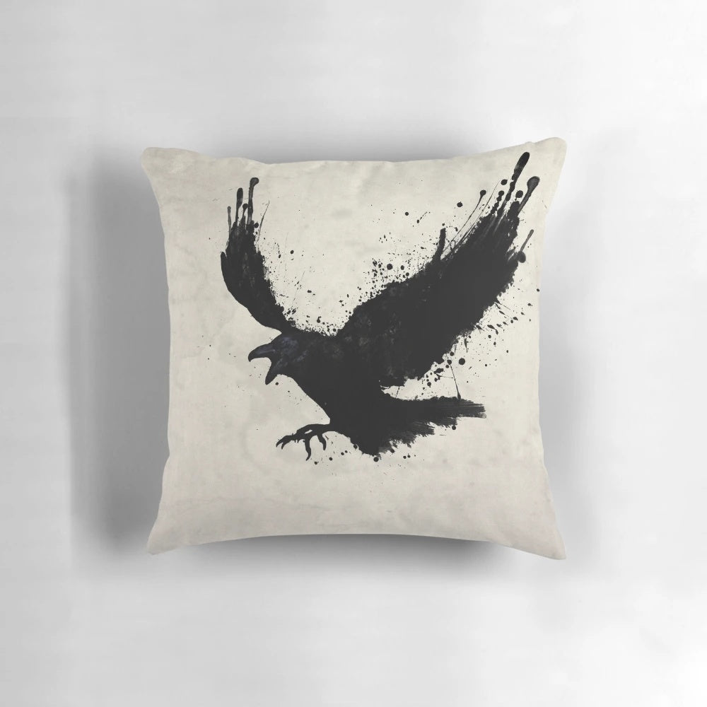 A black and white pillow with a sketch-style raven design, surrounded by splatters and drips