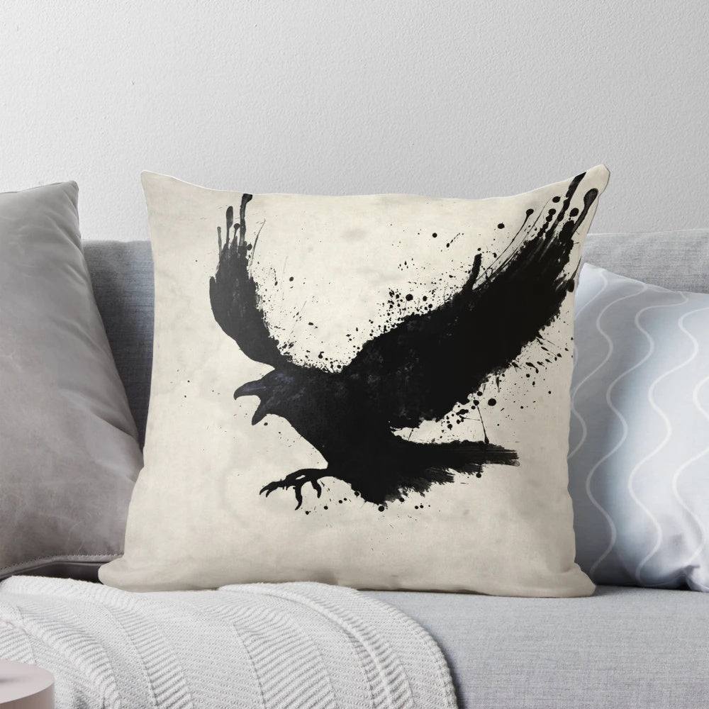 A black and white pillow with a sketch-style raven design, surrounded by splatters and drips