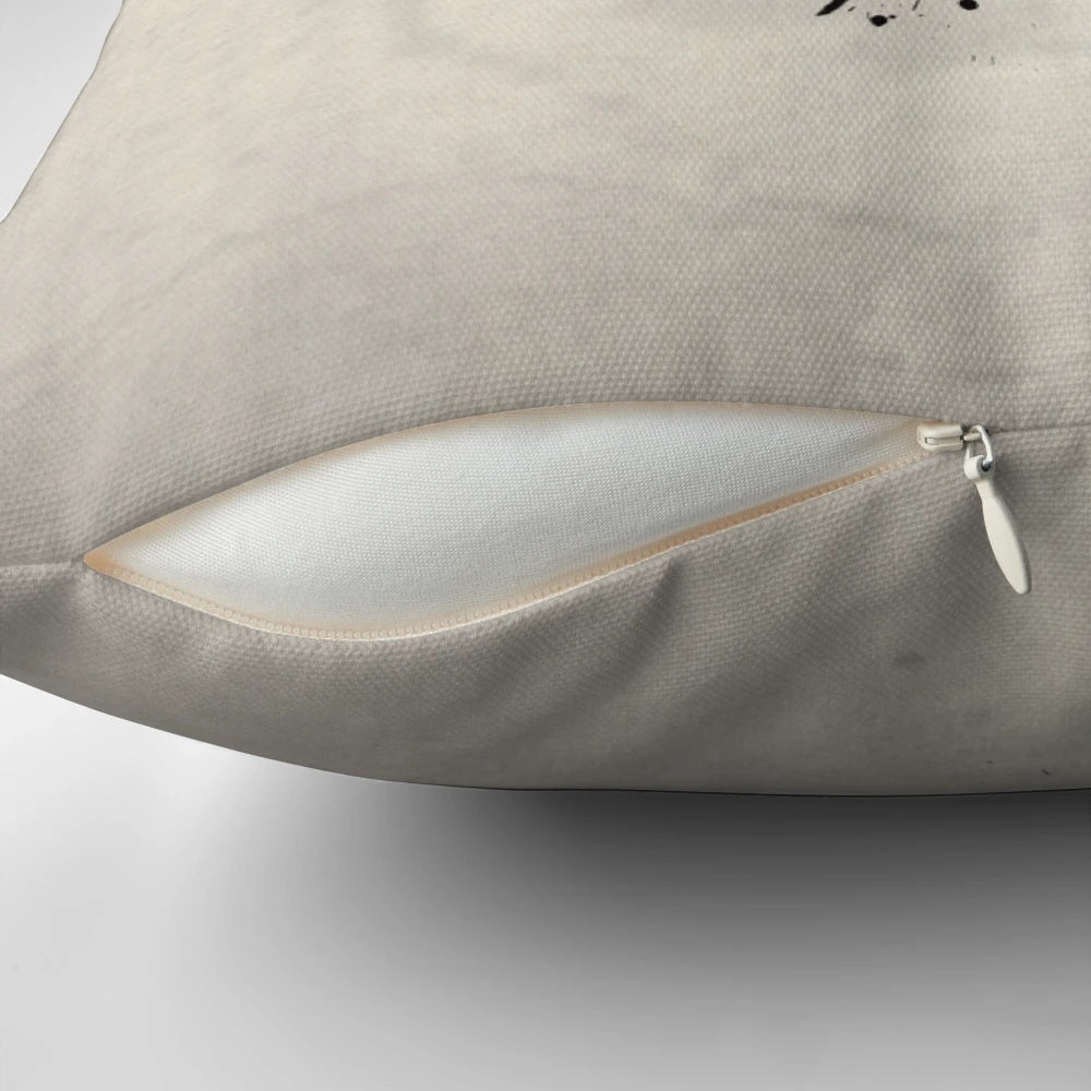 A black and white pillow with a sketch-style raven design, surrounded by splatters and drips