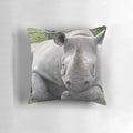 A black rhino resting its head on its forearm, looking relaxed in its natural environment.