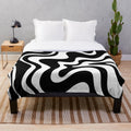Retro abstract plush blanket with a trippy swirly pattern in black and white