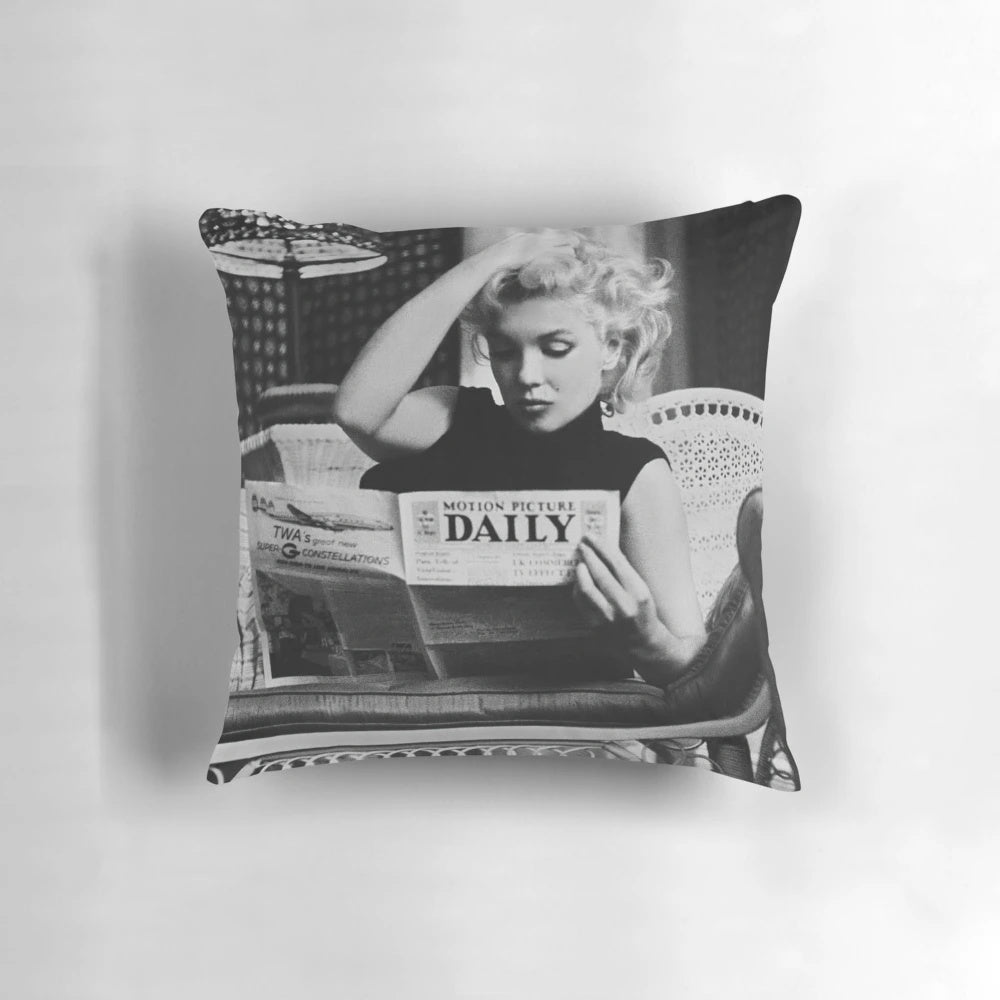 Retro black and white photograph of Marilyn Monroe reading a newspaper, featured on a decorative pillow.