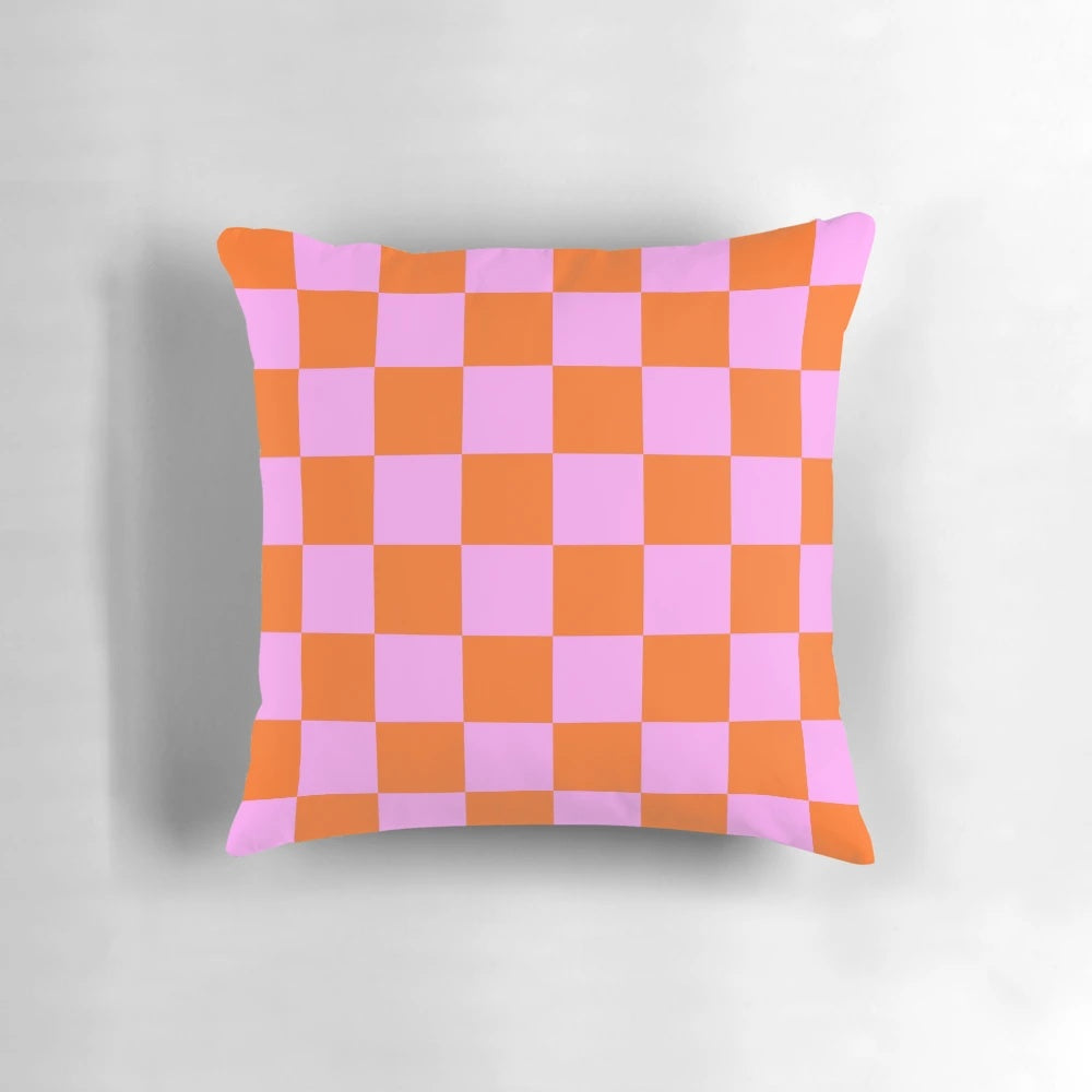 Vibrant checkerboard pattern pillow in shades of orange, red, and pink with a retro geometric design