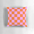 Vibrant checkerboard pattern pillow in shades of orange, red, and pink with a retro geometric design