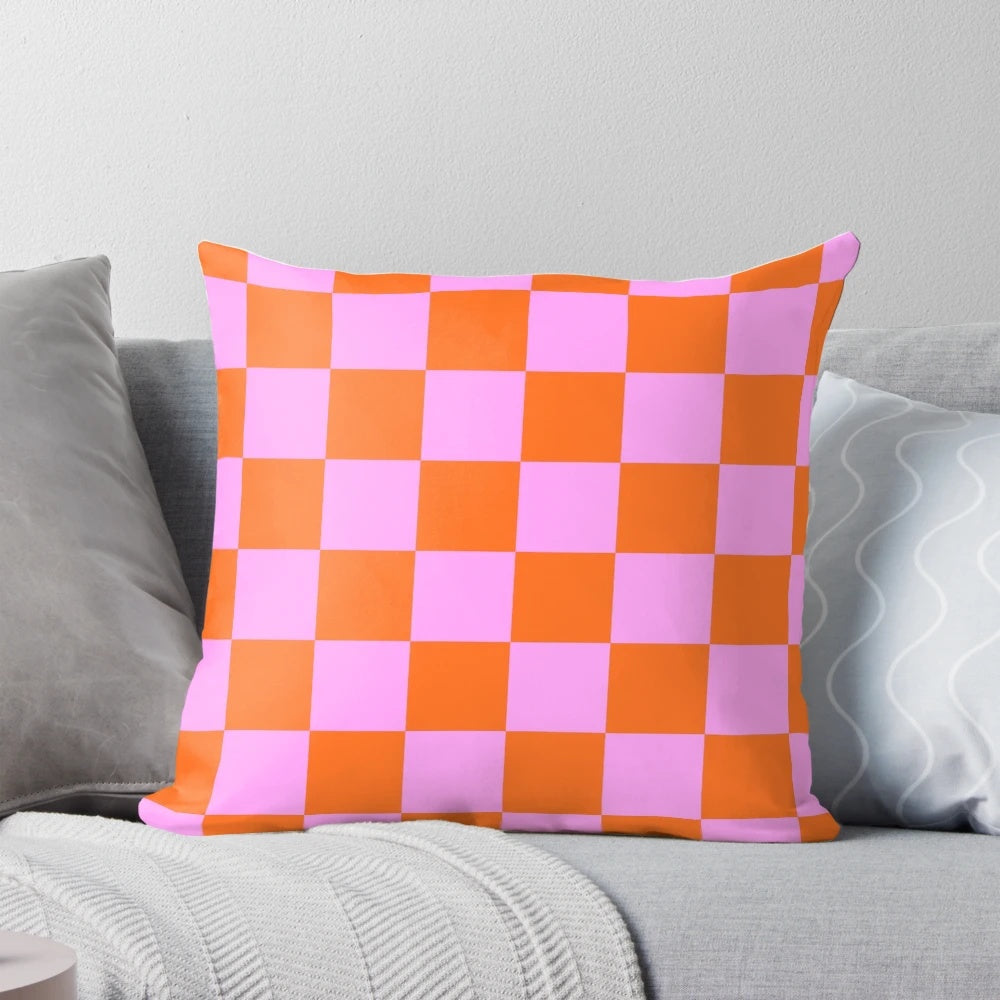 Vibrant checkerboard pattern pillow in shades of orange, red, and pink with a retro geometric design