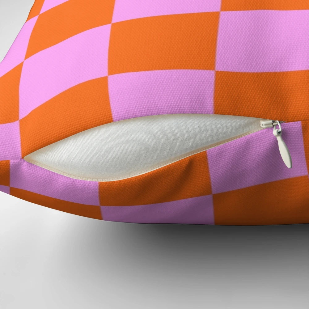 Vibrant checkerboard pattern pillow in shades of orange, red, and pink with a retro geometric design