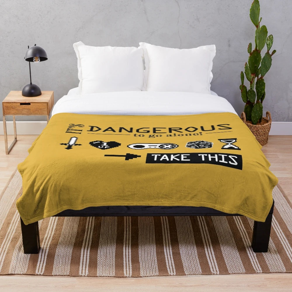 Plush blanket with gaming icons and "It's Dangerous to Go Alone" design