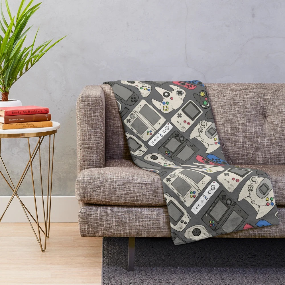 Plush blanket featuring a pattern of classic video game controllers