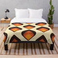 Mid-century modern style plush blanket with geometric tear drop pattern in orange and brown colors