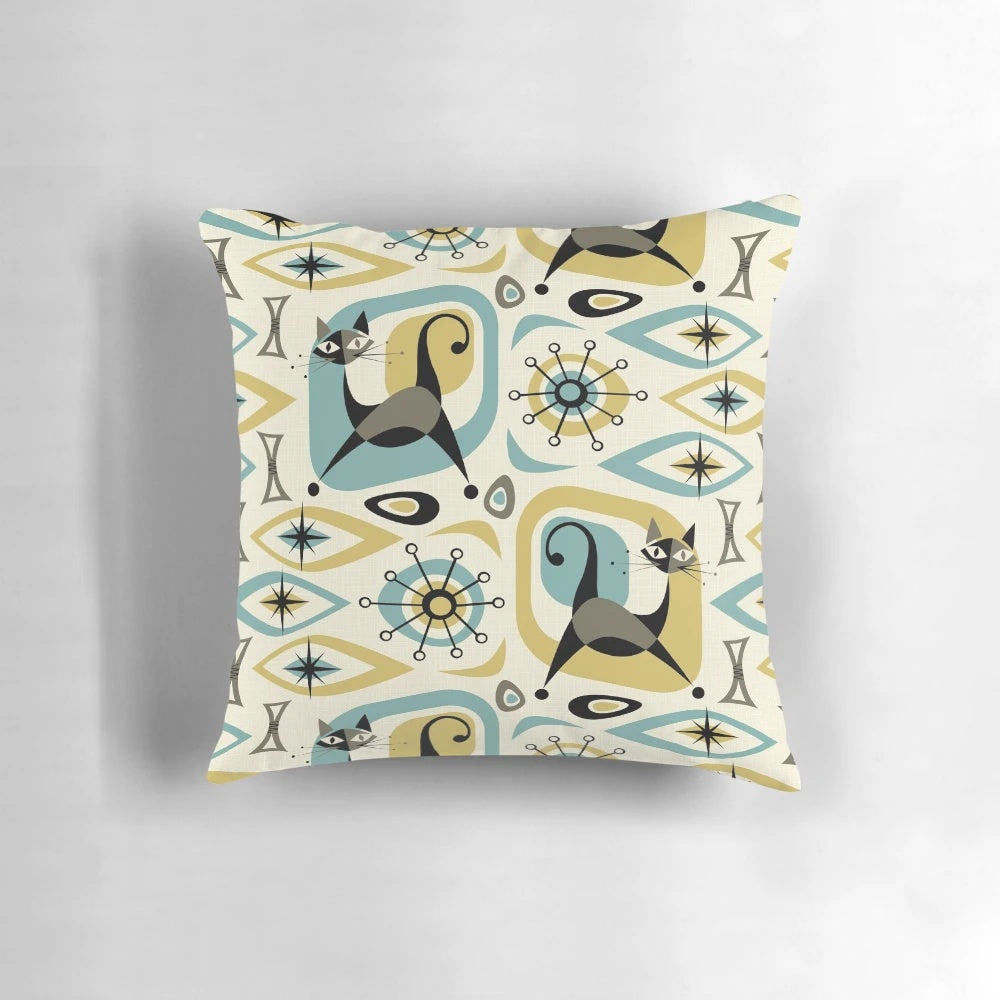 A vibrant mid-century style pillow featuring an abstract design with playful atomic-inspired cats in shades of blue, gold, and gray.