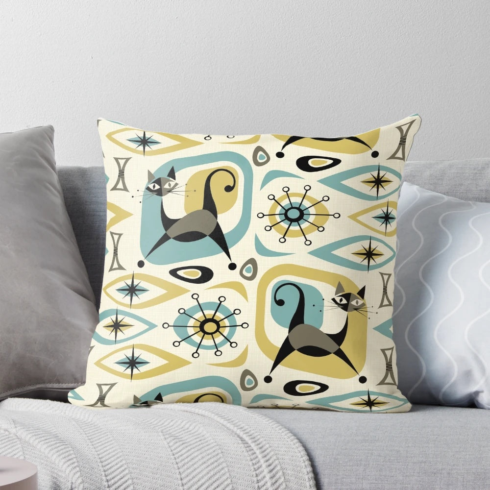 A vibrant mid-century style pillow featuring an abstract design with playful atomic-inspired cats in shades of blue, gold, and gray.
