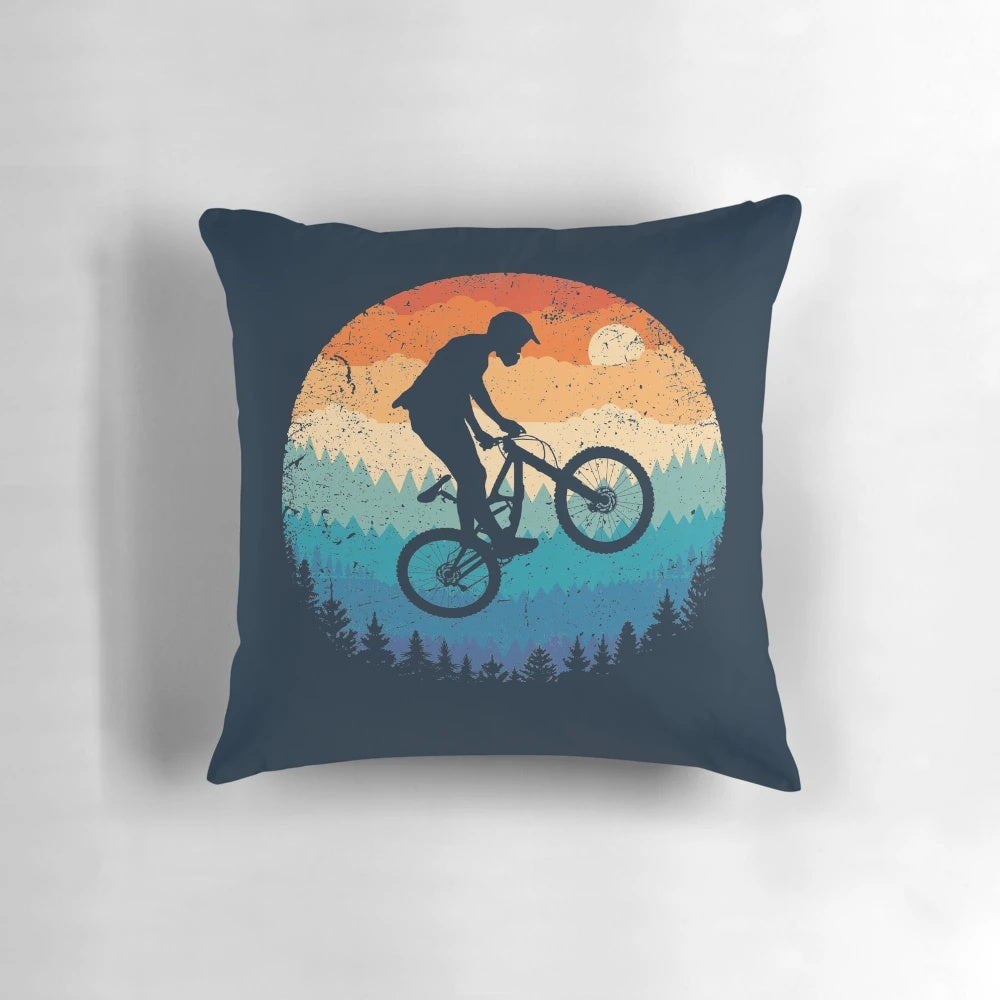 Vintage-inspired mountain biking pillow featuring a cyclist jumping over a sunset landscape