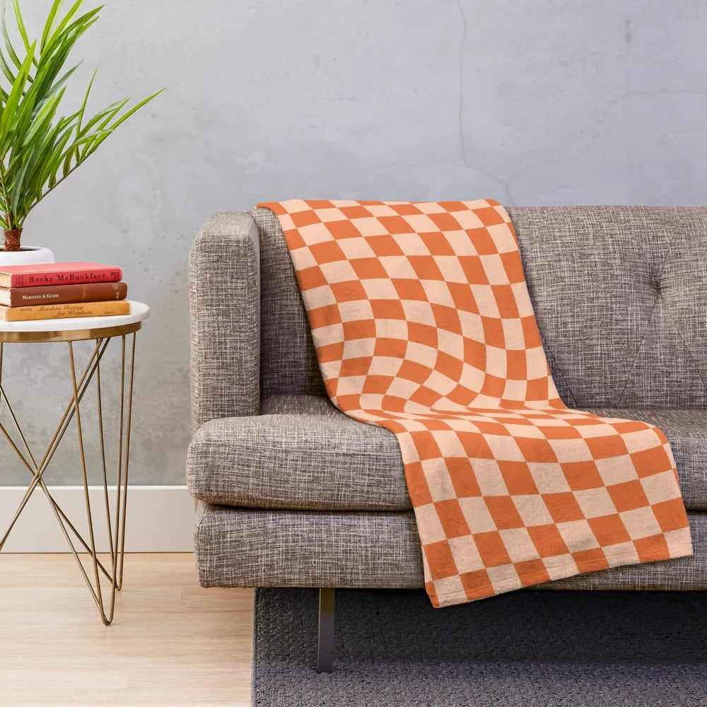 Cozy plush blanket with a vibrant orange checkered and wavy pattern, featuring a retro geometric design