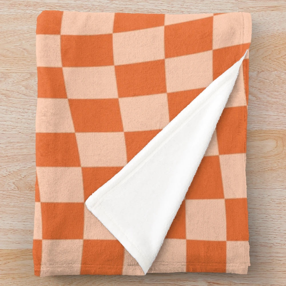 Cozy plush blanket with a vibrant orange checkered and wavy pattern, featuring a retro geometric design