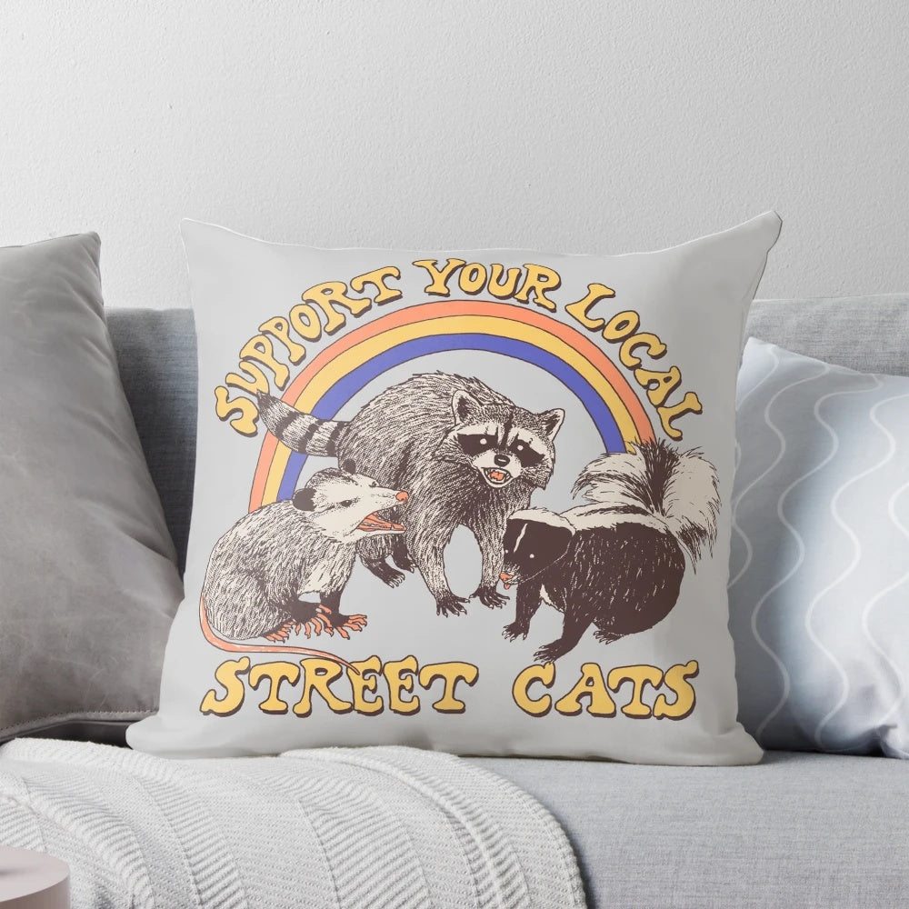 A colorful retro-style pillow featuring a design of street cats, possums, skunks, and raccoons in a vintage 80s style.