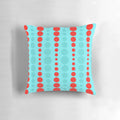 Closeup of a retro-styled throw pillow in a turquoise and red polka dot pattern, representing 1960s mid-century modern design.