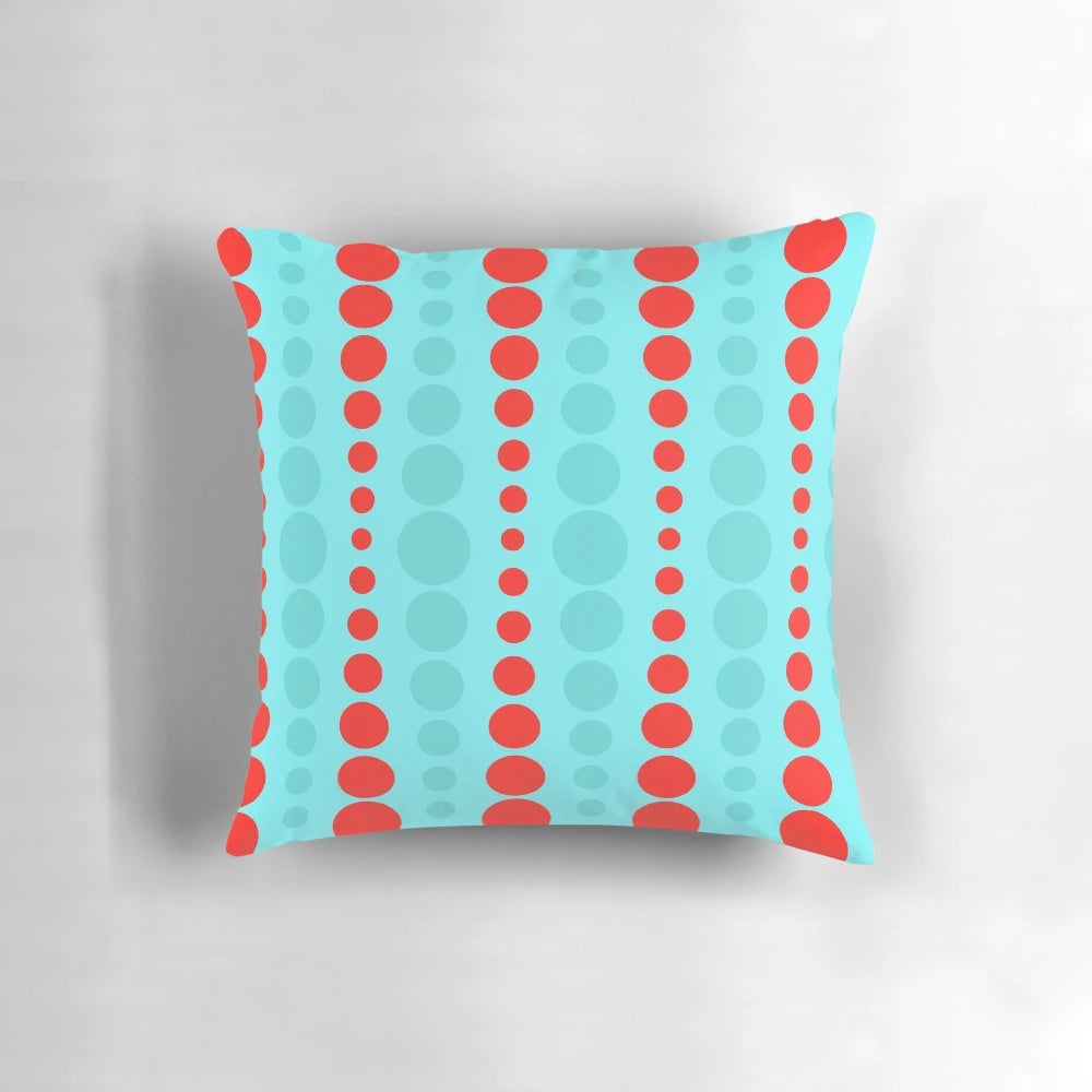 Closeup of a retro-styled throw pillow in a turquoise and red polka dot pattern, representing 1960s mid-century modern design.
