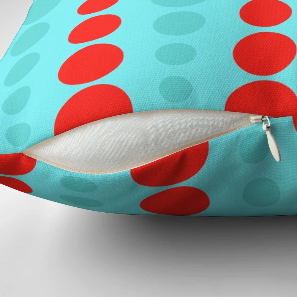 Closeup of a retro-styled throw pillow in a turquoise and red polka dot pattern, representing 1960s mid-century modern design.