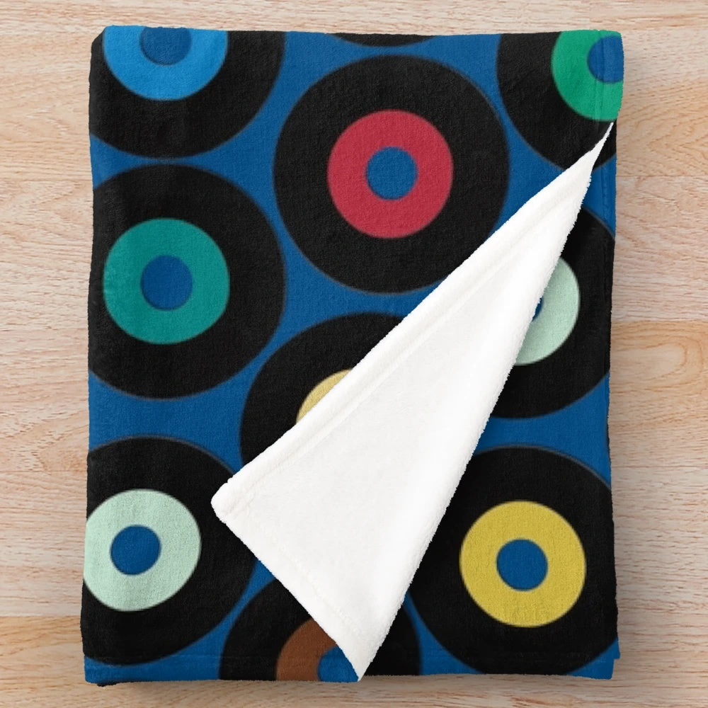 Blue plush blanket with retro vinyl record-inspired polka dot pattern and multicolor graphic design
