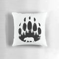 Black and white throw pillow featuring a bear paw print design against a forest landscape background.