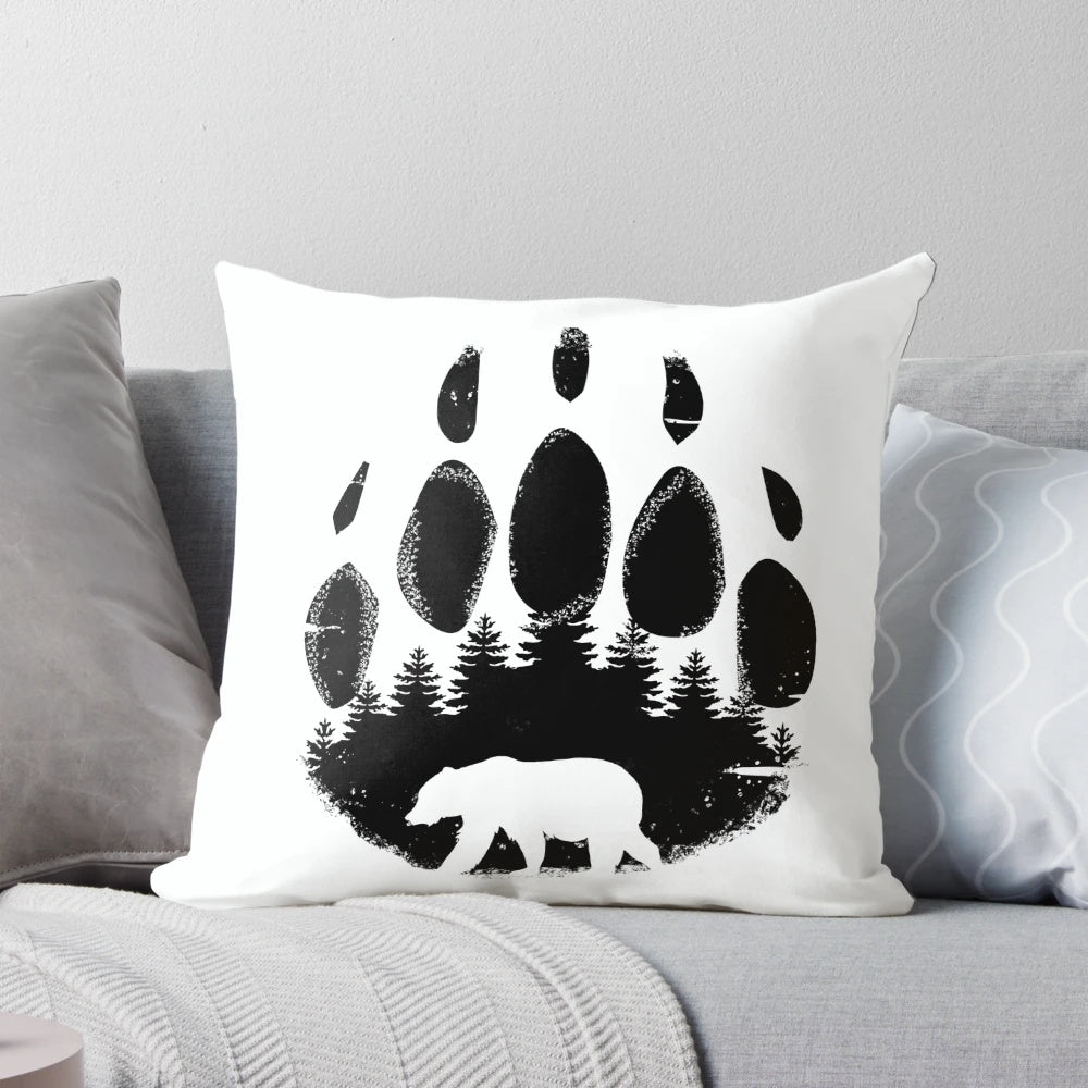 Black and white throw pillow featuring a bear paw print design against a forest landscape background.