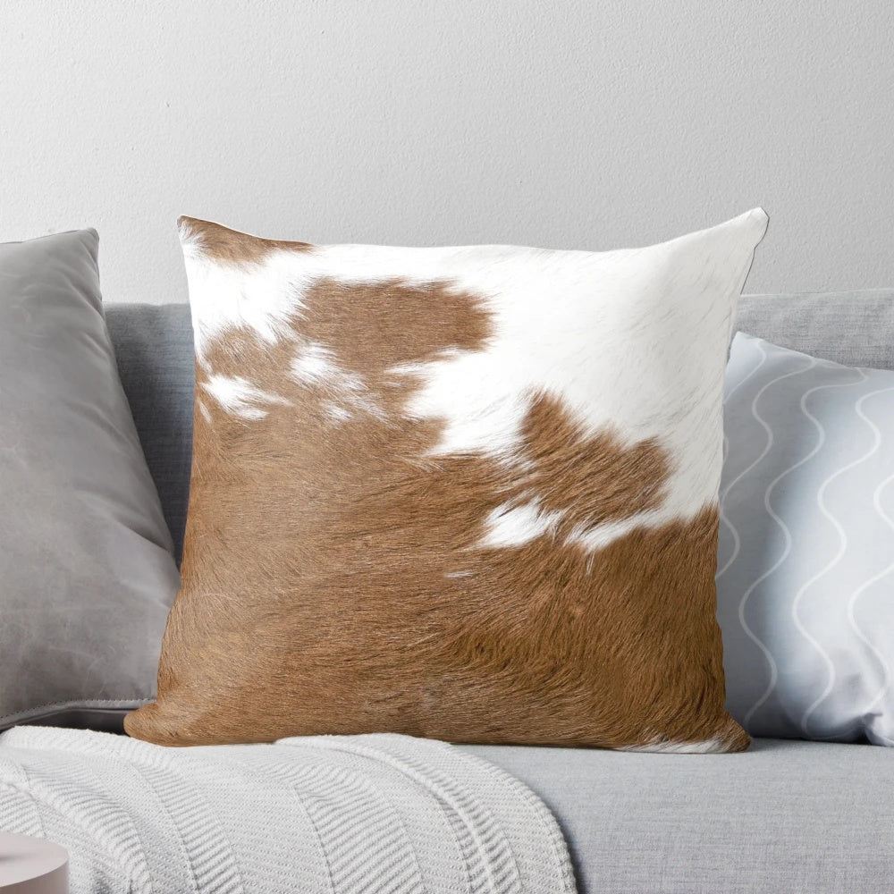 Rustic cow hide-inspired decorative pillow in brown and white tones, perfect for farmhouse or western-style home decor.