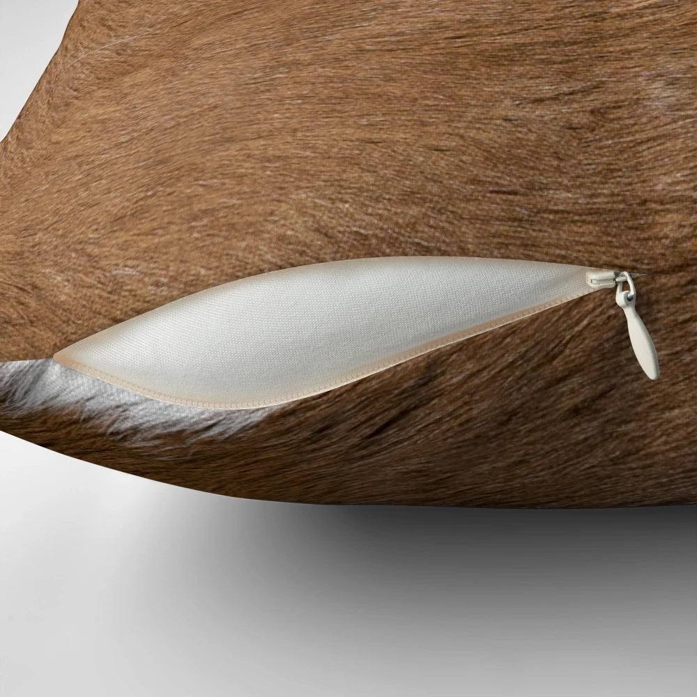 Rustic cow hide-inspired decorative pillow in brown and white tones, perfect for farmhouse or western-style home decor.