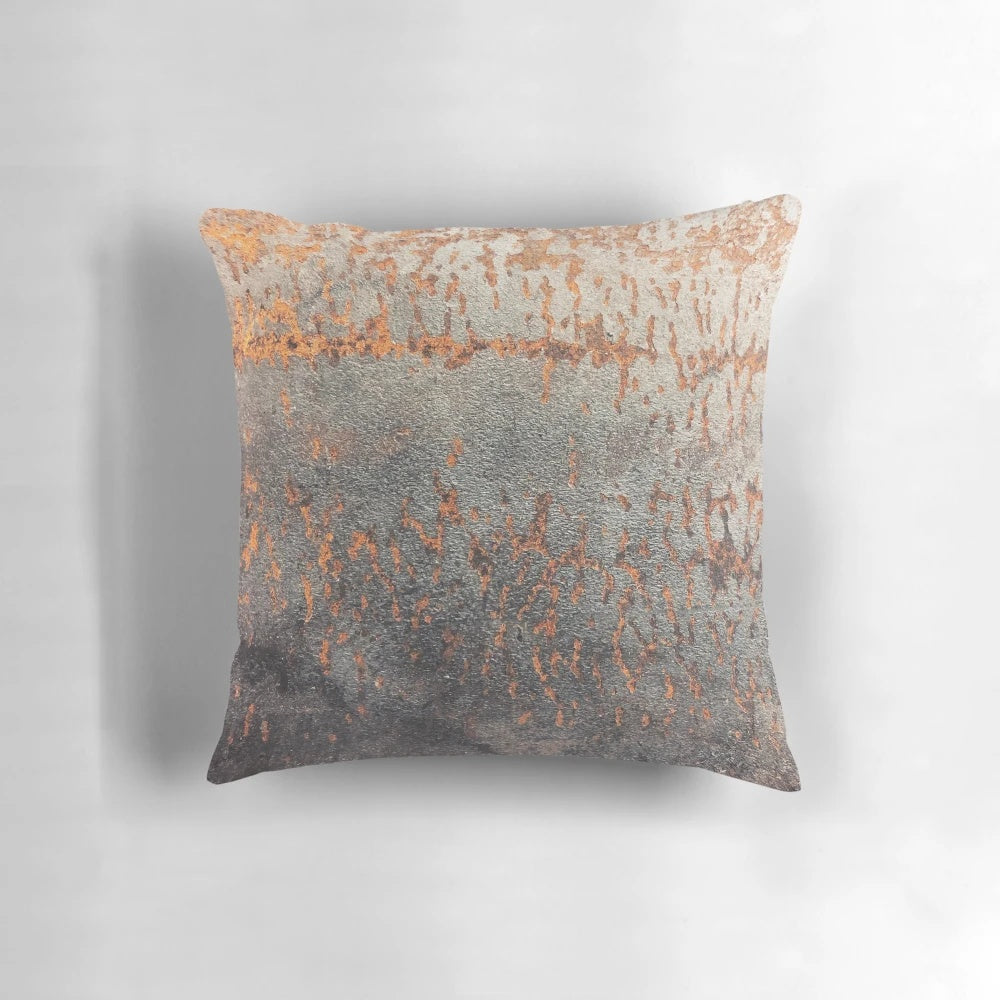 A rustic, distressed metal pillow with a textured, oxidized surface for an industrial-style home accent.