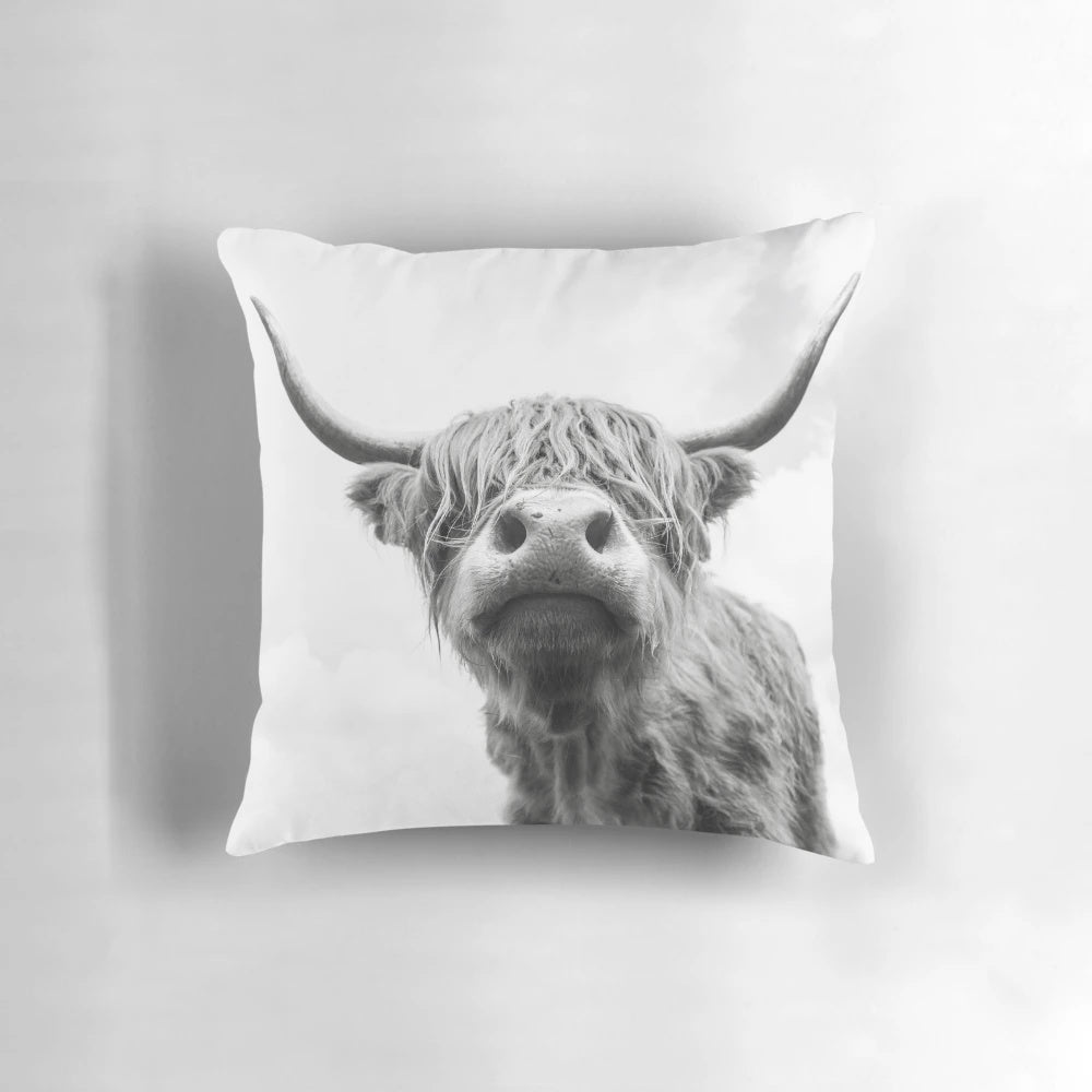 Black and white highland cow illustrated on a decorative farmhouse-style pillow