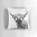 Black and white highland cow illustrated on a decorative farmhouse-style pillow