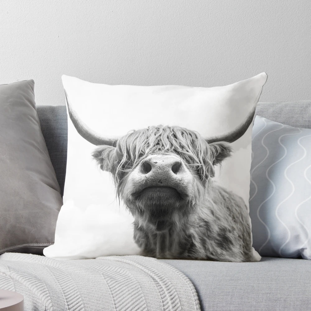 Black and white highland cow illustrated on a decorative farmhouse-style pillow