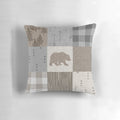 A rustic patchwork pillow in neutral tones featuring a bear design, perfect for woodland and camping themed home decor.