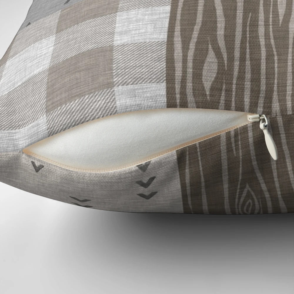 A rustic patchwork pillow in neutral tones featuring a bear design, perfect for woodland and camping themed home decor.