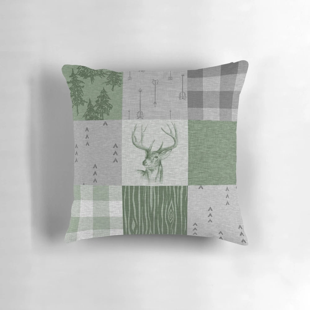 Rustic patchwork pillow with deer, trees, and arrow design in green and grey colors
