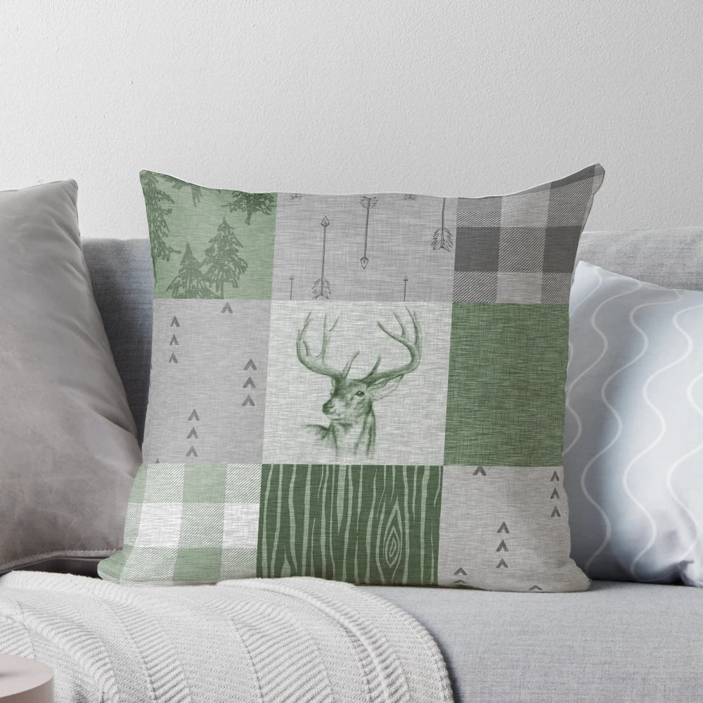 Rustic patchwork pillow with deer, trees, and arrow design in green and grey colors