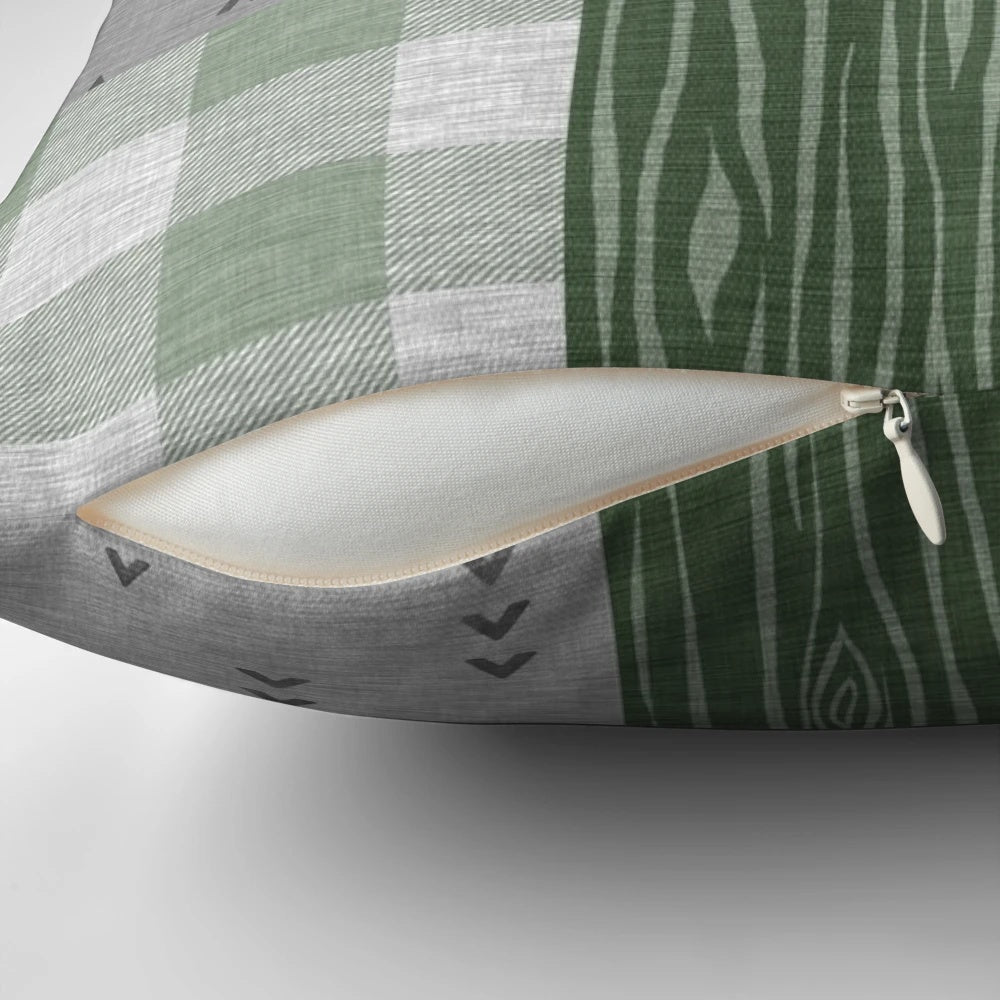 Rustic patchwork pillow with deer, trees, and arrow design in green and grey colors
