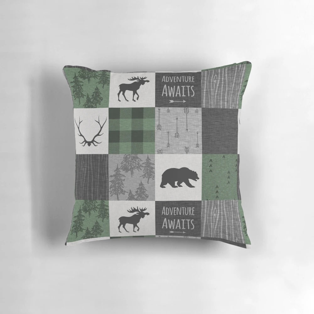 Rustic woodland patchwork throw pillow in shades of gray and green, featuring deer, moose, and other woodland elements.