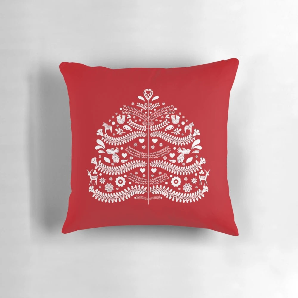 Closeup of a white Scandinavian-style Christmas tree printed on a red throw pillow, with snowflakes and floral accents.