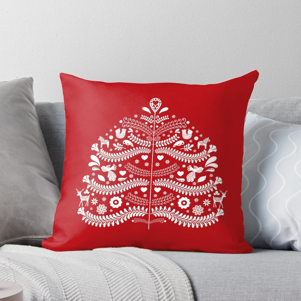 Closeup of a white Scandinavian-style Christmas tree printed on a red throw pillow, with snowflakes and floral accents.