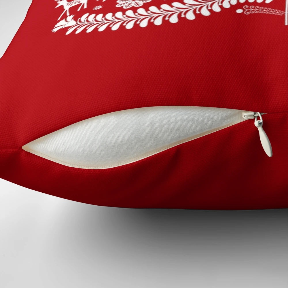 Closeup of a white Scandinavian-style Christmas tree printed on a red throw pillow, with snowflakes and floral accents.