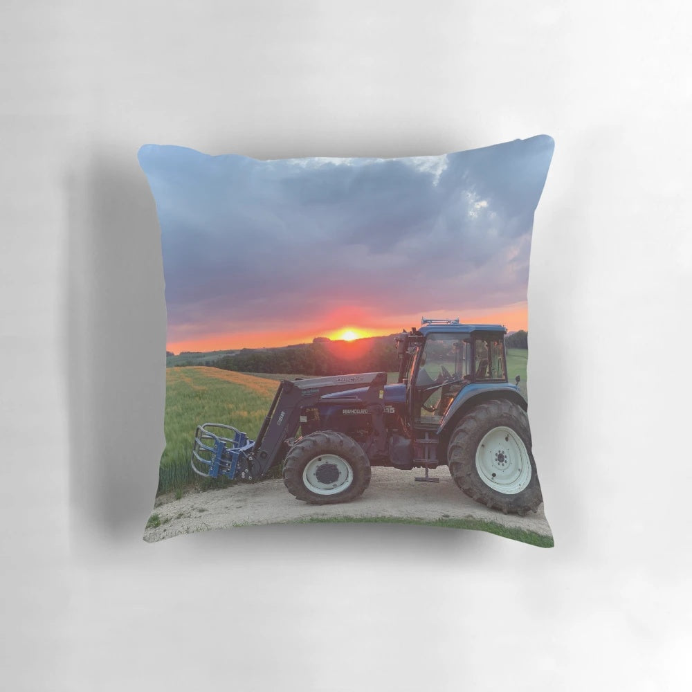 A vibrant sunset casts a warm glow over a New Holland tractor in a pastoral landscape.