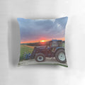 A vibrant sunset casts a warm glow over a New Holland tractor in a pastoral landscape.