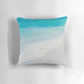 Decorative beach pillow featuring a vibrant seascape painting of crashing waves and a sandy shore.