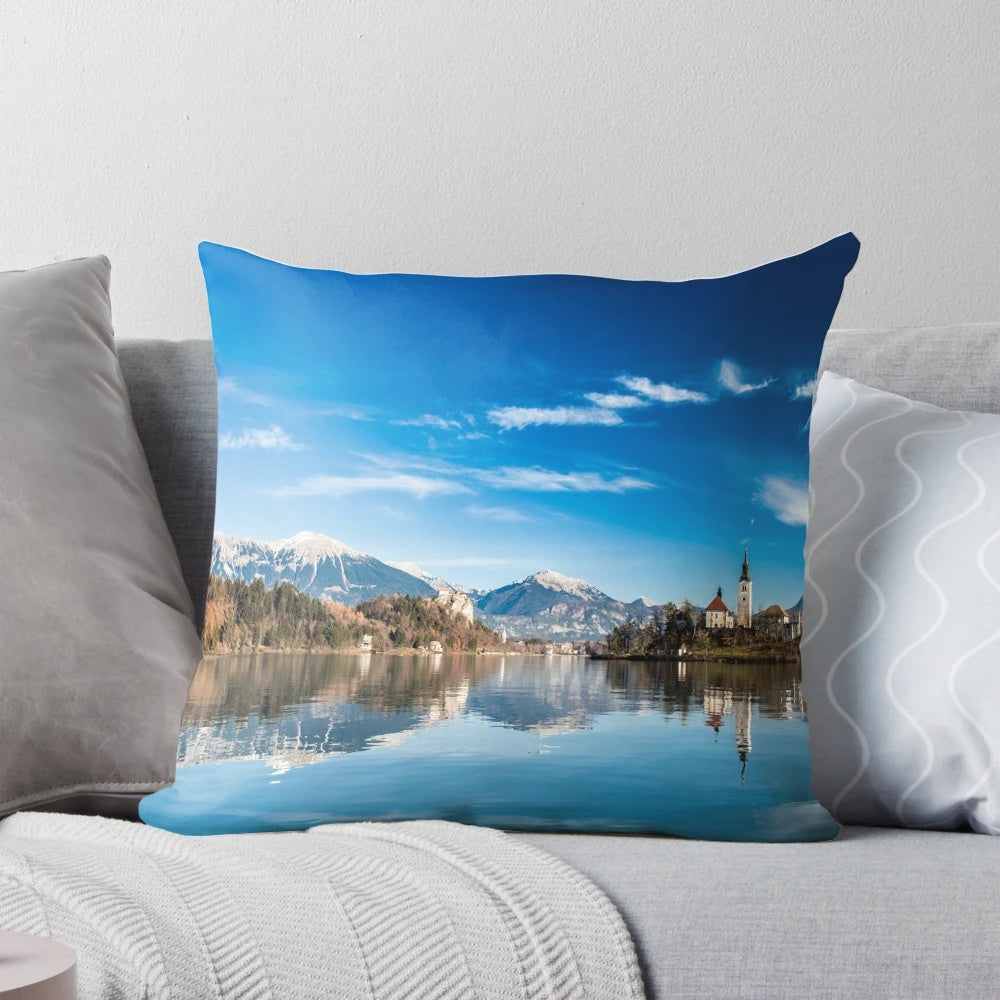 Peaceful landscape of the Lake of Bled in Slovenia, with a church and trees reflecting in the calm waters at sunrise.