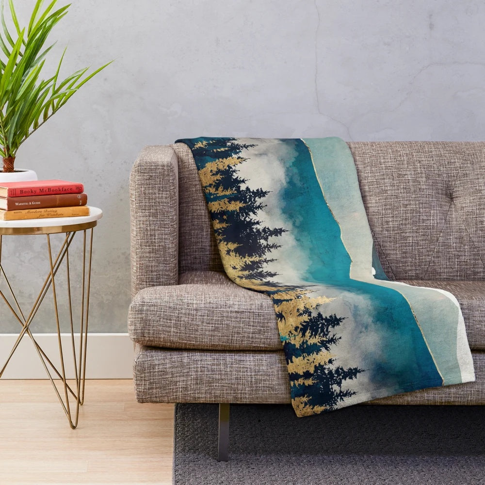 Plush blanket with abstract, nature-inspired design in shades of blue, green, and gold