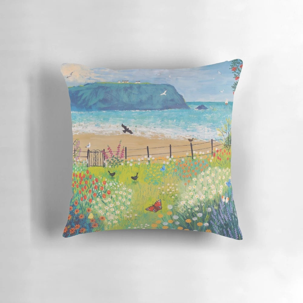 Decorative pillow featuring a painting of a garden by the sea with butterflies and birds