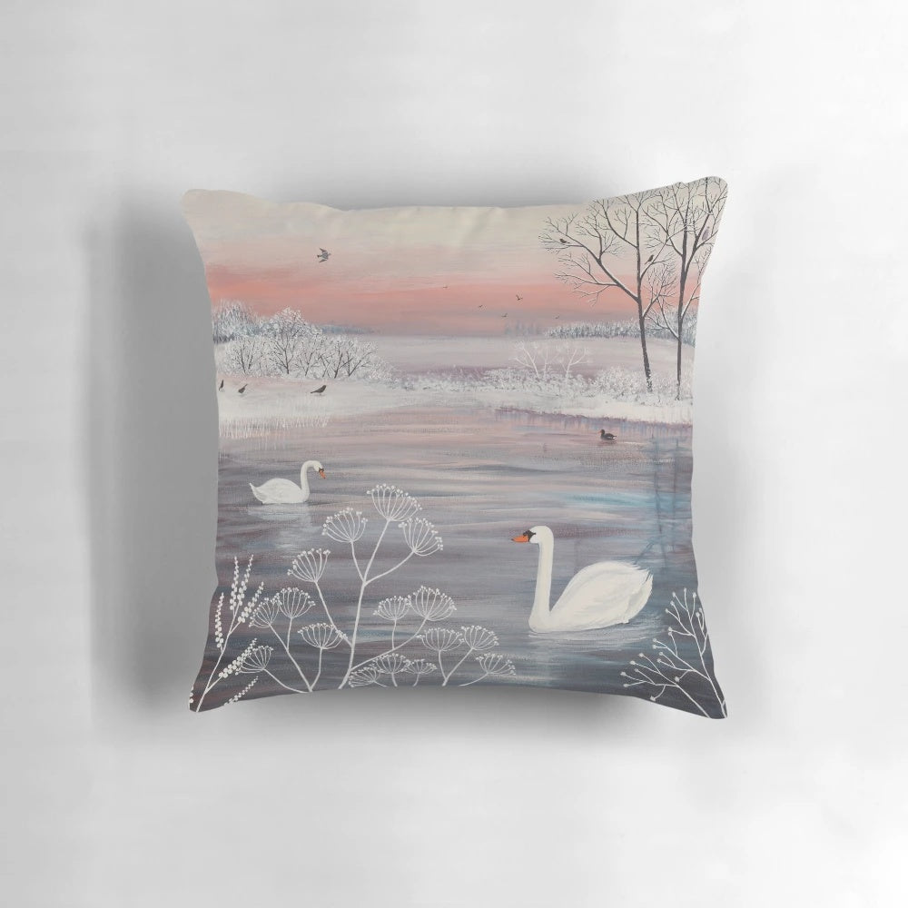 A beautiful throw pillow featuring a serene winter landscape with snow-covered trees and a pair of graceful swans.